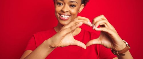 woman making a heart with her hands on red background