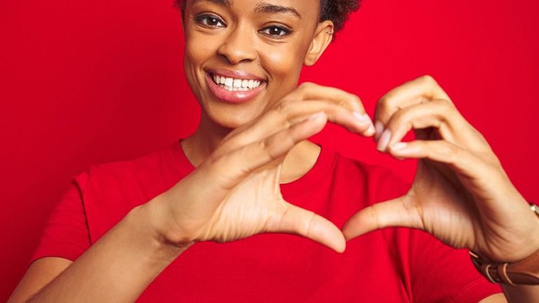 woman making a heart with her hands on red background