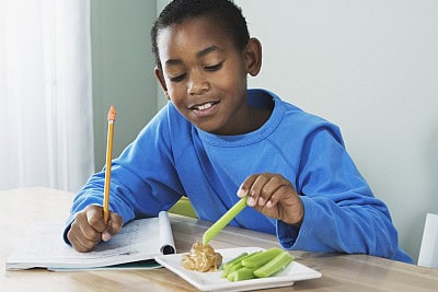 boy doing homework and having an after school snack