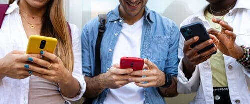 group of college students young adults on cell phones